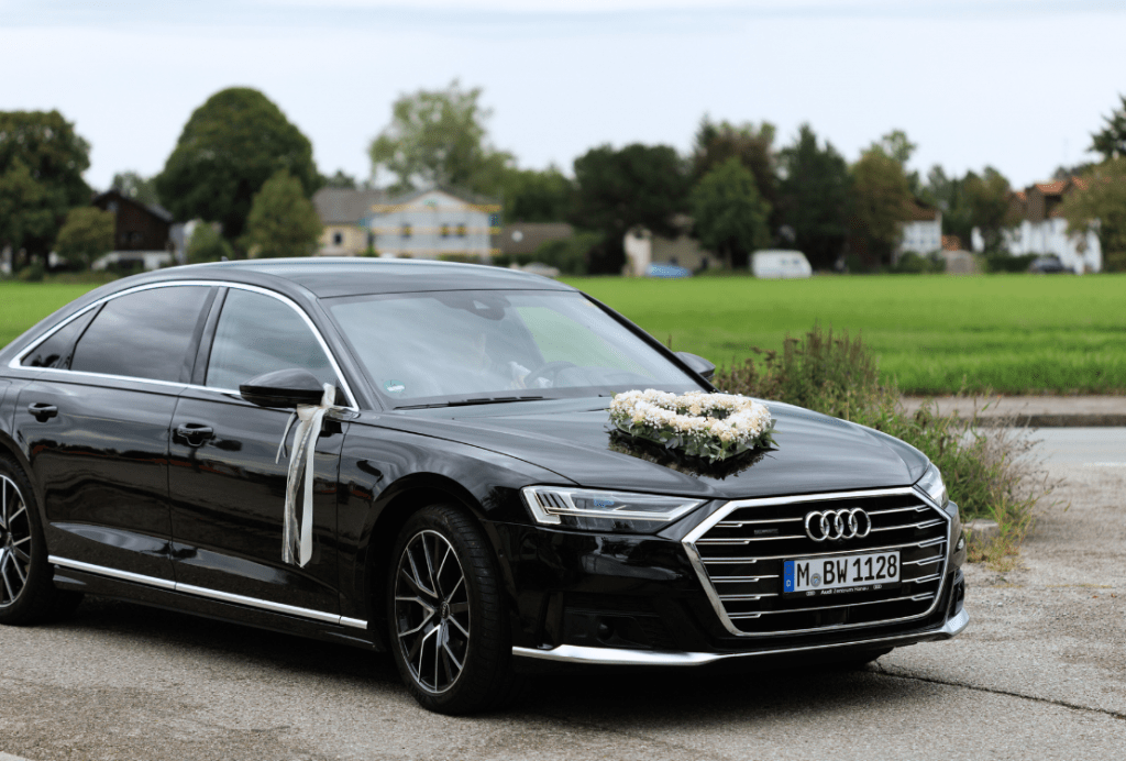 Schwarze Audi A8 L Limousine mit Blumenschmuck auf der Motorhaube, bereit für eine exklusive Hochzeitsfahrt in Vaterstetten als Alternative zum Taxi.